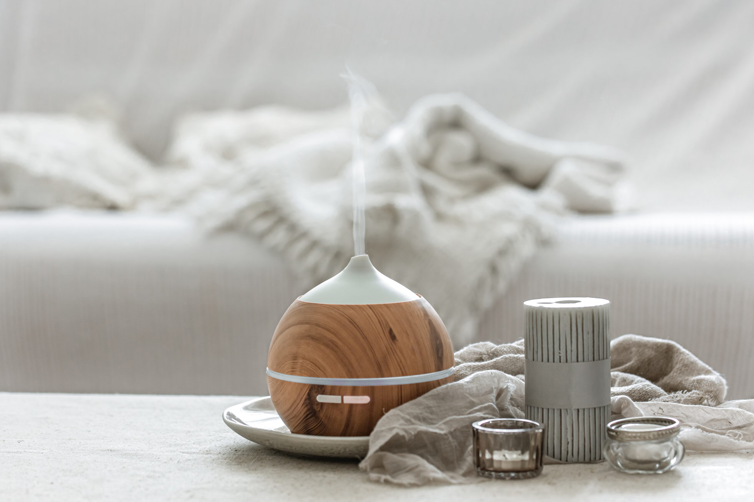 Cozy home composition with air humidifier and candles on blurred background.
